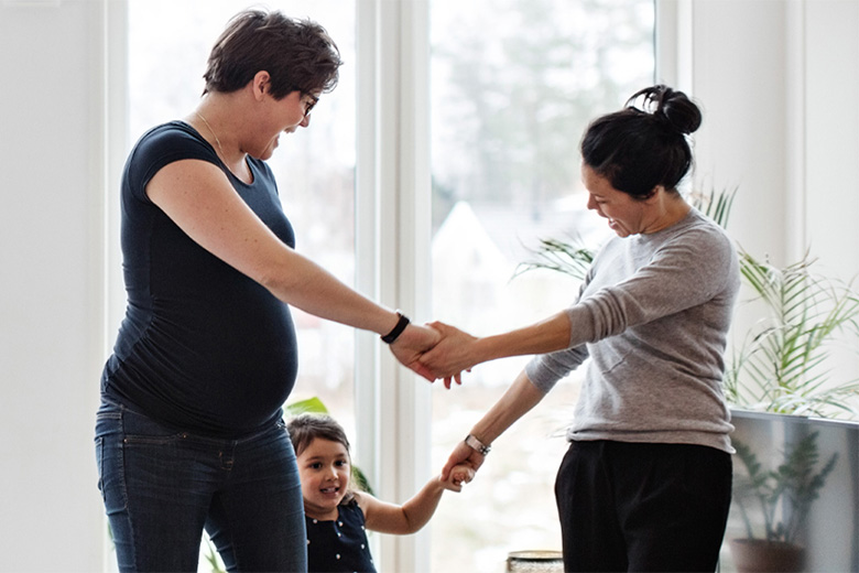 Two moms dance with their daughter